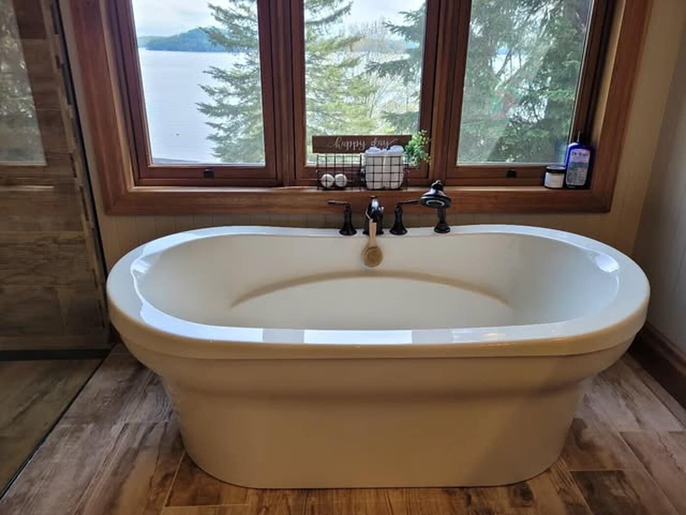 Freestanding soaker tub in a cleaned lakeside bathroom, with the water visible through the window